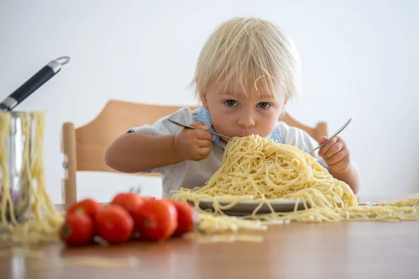 Little baby boy, toddler child, eating spaghetti for lunch and m Stock Photo
