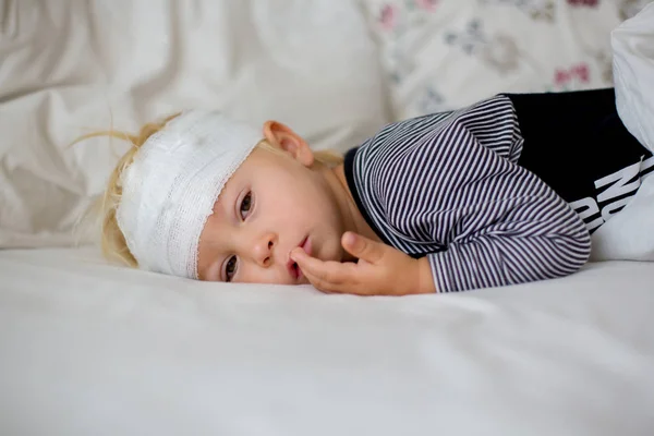Little toddler boy with head injury, lying in bed, tired — Stock Image Little toddler boy with head injury, lying in bed, tired Royalty Free Stock Images