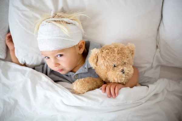 Little toddler boy with head injury, lying in bed, tired — Stock Image Little toddler boy with head injury, lying in bed, tired Stock Photo