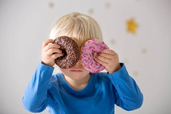 Schattig zoet blond kind, spelen en eten donuts — Stockfoto