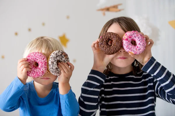 Schattig zoet blond kind, spelen en eten donuts — Stockfoto