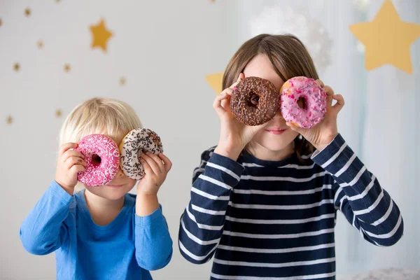 Schattig zoet blond kind, spelen en eten donuts — Stockfoto