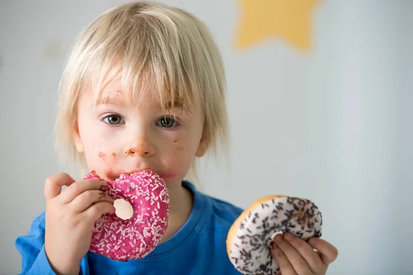 Schattig zoet blond kind, spelen en eten donuts — Stockfoto