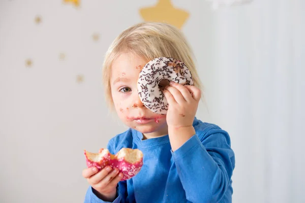 Schattig zoet blond kind, spelen en eten donuts — Stockfoto