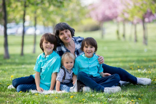 Avó e filhos em um belo parque de primavera florescendo — Fotografia de Stock