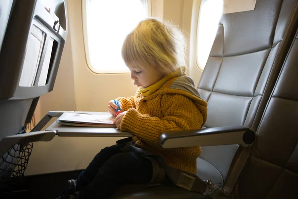 Blonde toddler boy, flying with airplane,enjoying the flight