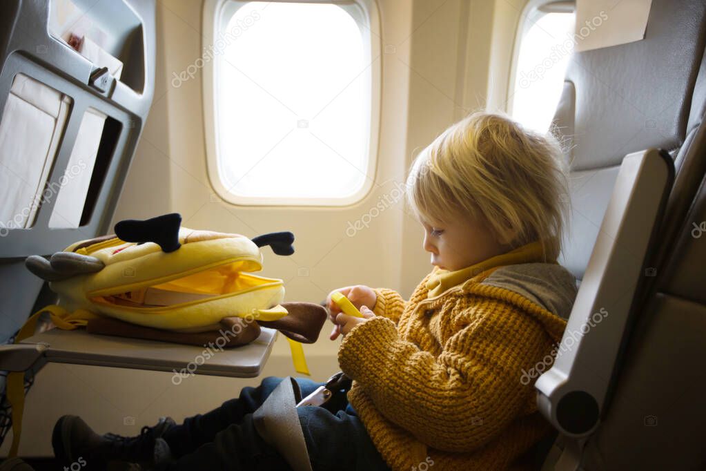 Blonde toddler boy, flying with airplane,enjoying the flight