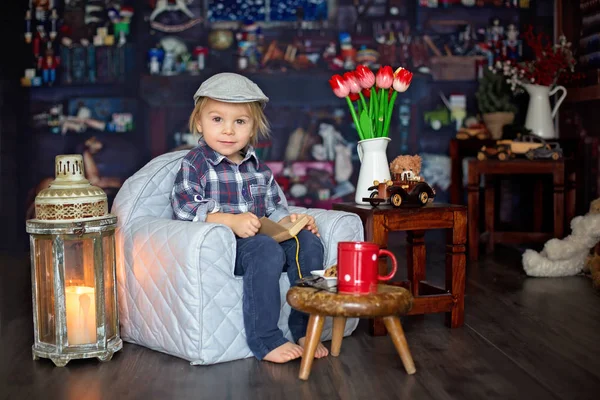 Dulce niño, con gafas, leyendo un libro y bebiendo —  Fotos de Stock