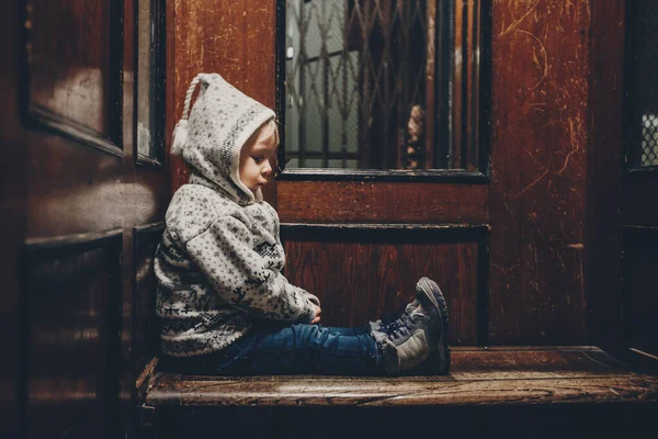 Γλυκό μικρό ξανθό αγόρι, κάθεται σε ένα παλιό ξύλινο ασανσέρ ή l — Φωτογραφία Αρχείου