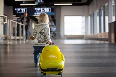 Sarışın çocuk ailesiyle uçakla seyahat ediyor, koşuyor.