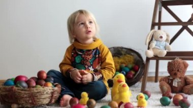 Küçük çocuk, sarışın çocuk paskalya yumurtalarıyla oynuyor. Çocuklar yumurta ve civcivlerle oynar.