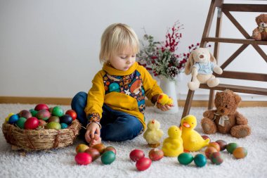 Toddler child, blonde boy playing with Easter eggs. Children pla