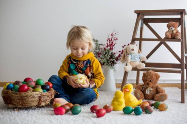 Toddler child, blonde boy playing with Easter eggs. Children pla