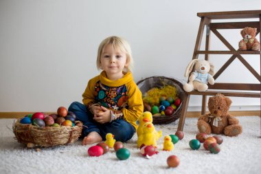 Toddler child, blonde boy playing with Easter eggs. Children pla
