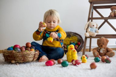 Toddler child, blonde boy playing with Easter eggs. Children pla
