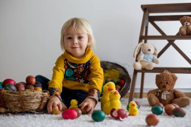Toddler child, blonde boy playing with Easter eggs. Children pla