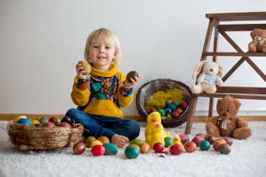 Toddler child, blonde boy playing with Easter eggs. Children pla