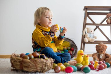 Toddler child, blonde boy playing with Easter eggs. Children pla