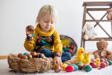 Toddler child, blonde boy playing with Easter eggs. Children pla