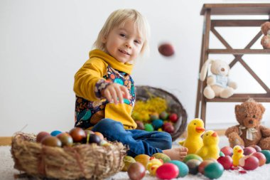 Toddler child, blonde boy playing with Easter eggs. Children pla