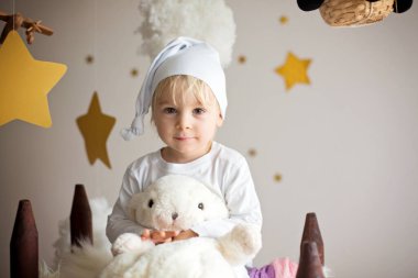 Cute child, blonde boy, playing at night with colorful scarf and