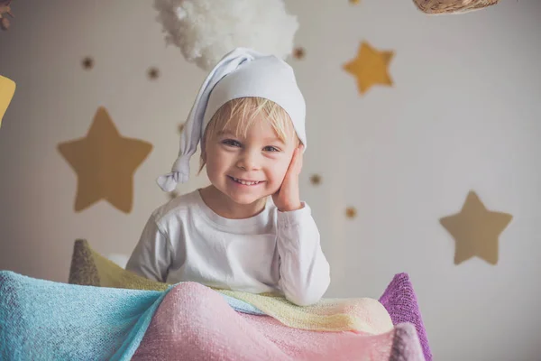 Niedliches Kind, blonder Junge, spielt nachts mit buntem Schal und — Stockfoto