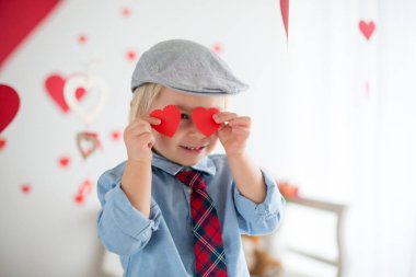 Cute blonde toddler boy, holding heart toy and playing with hear