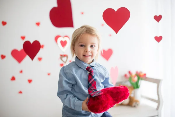 Lindo niño rubio, sosteniendo el juguete del corazón y jugando con escuchar —  Fotos de Stock