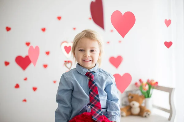 Lindo niño rubio, sosteniendo el juguete del corazón y jugando con escuchar — Foto de Stock