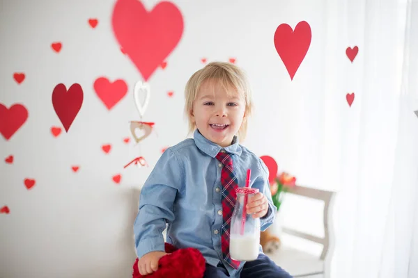 Lindo niño rubio, sosteniendo el juguete del corazón y jugando con escuchar — Foto de Stock