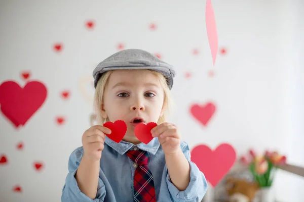 Leuke blonde peuter jongen, met hart speelgoed en spelen met horen — Stockfoto