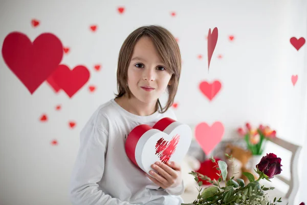 Cute long haired school boy, holding heart box and red roses and — Stok fotoğraf