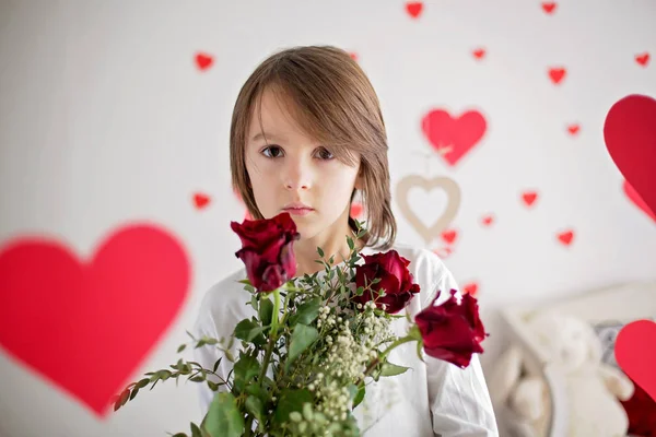 Bonito menino da escola de cabelos longos, segurando caixa de coração e rosas vermelhas e — Fotografia de Stock