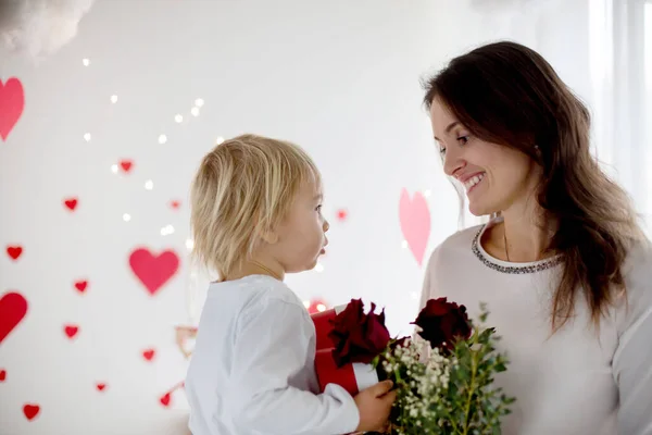 Cute blonde toddler boy, holding box in heart shape and flowers — 스톡 사진