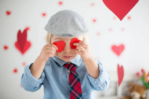 Bonito loira criança menino, segurando coração brinquedo e brincando com ouvir — Fotografia de Stock