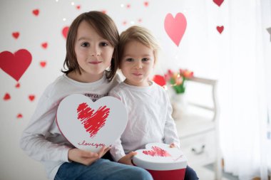 Cute blonde toddler boy and his older brother, holding box in he
