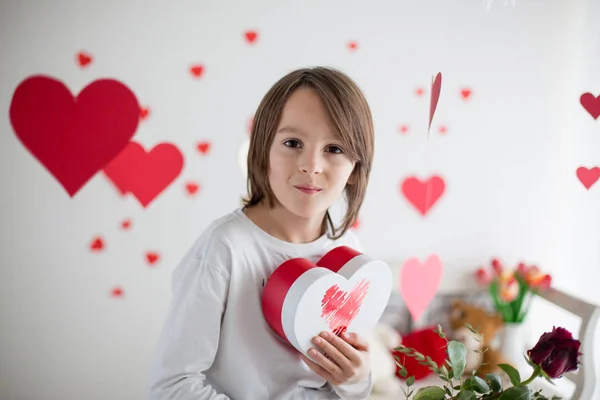 Cute long haired school boy, holding heart box and red roses and — Stok fotoğraf