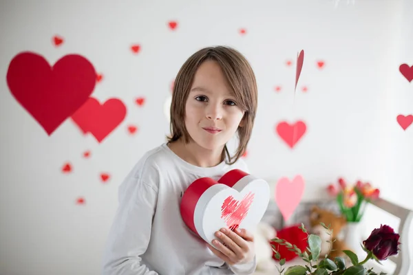 Cute long haired school boy, holding heart box and red roses and — Stock Photo, Image