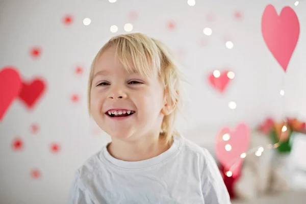 Cute blonde toddler boy, holding box in heart shape and flowers — ストック写真