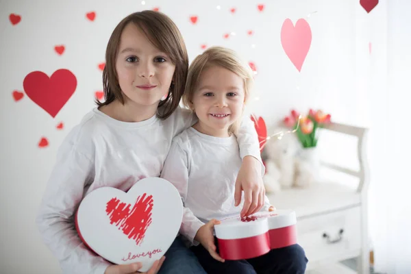 Niedliche blonde Kleinkind Junge und sein älterer Bruder, hält Box in er — Stockfoto