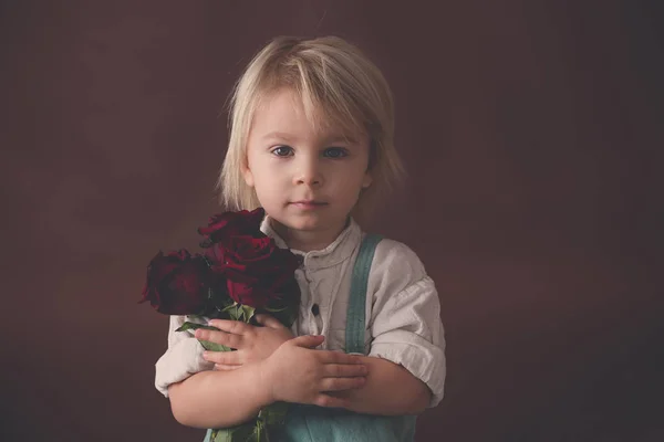 Beautiful toddler boy, holding red roses for mother's day — Stok fotoğraf