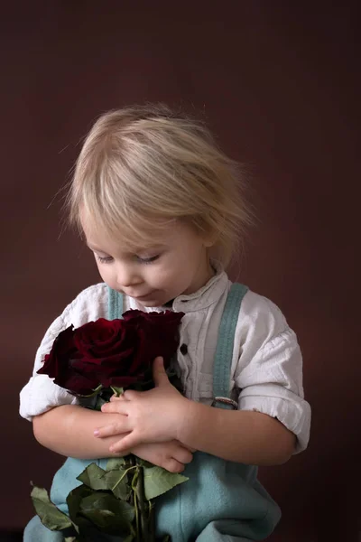 Beautiful toddler boy, holding red roses for mother's day — Stok fotoğraf