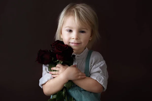 Menino da criança bonita, segurando rosas vermelhas para o dia da mãe — Fotografia de Stock