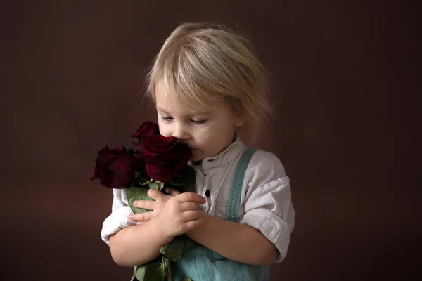 Beautiful toddler boy, holding red roses for mother's day — Stok fotoğraf