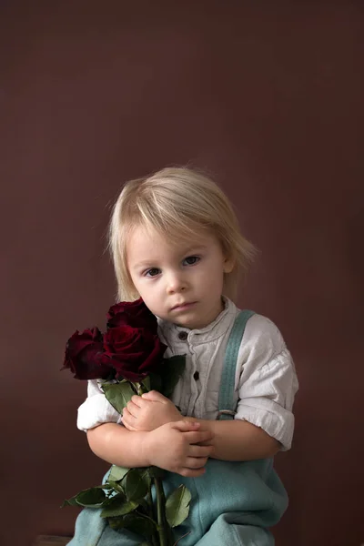 Beau petit garçon, tenant des roses rouges pour la fête des mères — Photo