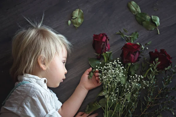 Beautiful toddler boy, holding red roses for mother's day — ストック写真