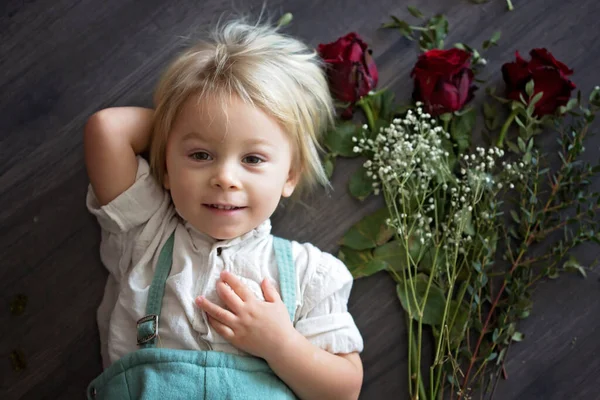 Beautiful toddler boy, holding red roses for mother's day — Stok fotoğraf