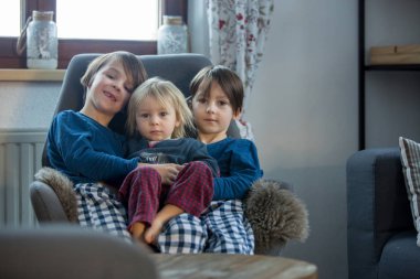 Anaokulu çocukları ve yeni yürümeye başlayan çocuklar sallanan sandalyede oturup sarılıyorlar.