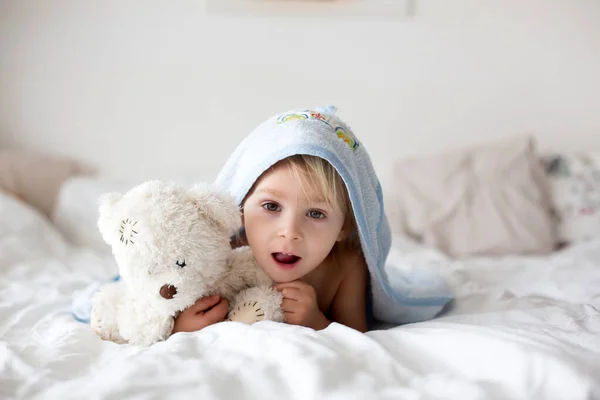 かわいい金髪の幼児の男の子 お風呂の後のベッドでリラックスして 喜んで笑って — ストック写真