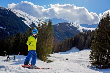 Çocuğum, güneşli bir günde kış kayak merkezinde kayak yapmak, manzaranın tadını çıkarmak